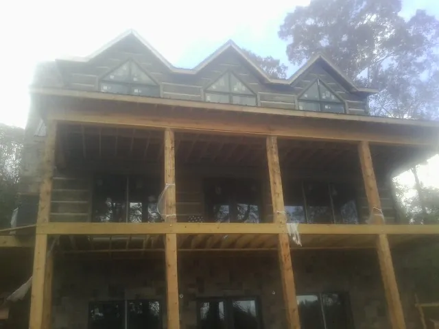 Dormers and porch framing on a large log home under construction — Roof Coating work by our crew in Nome